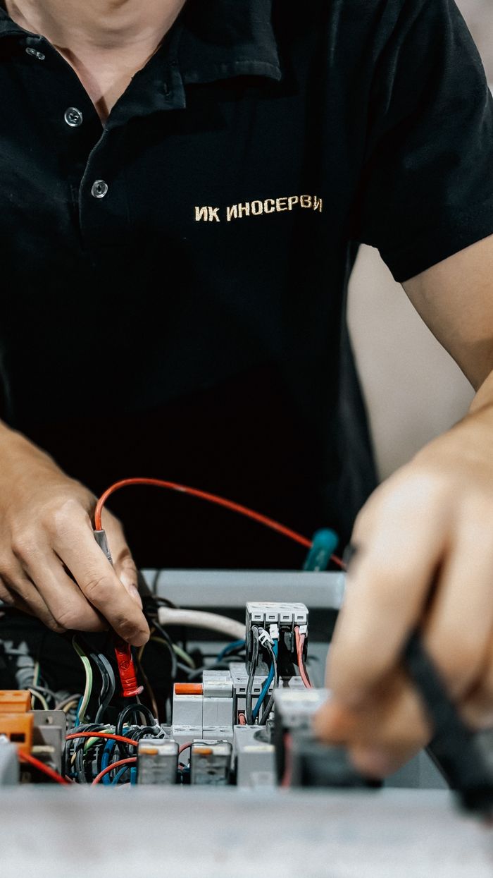 Electrical technician repairing a circuit board with precision tools indoors.